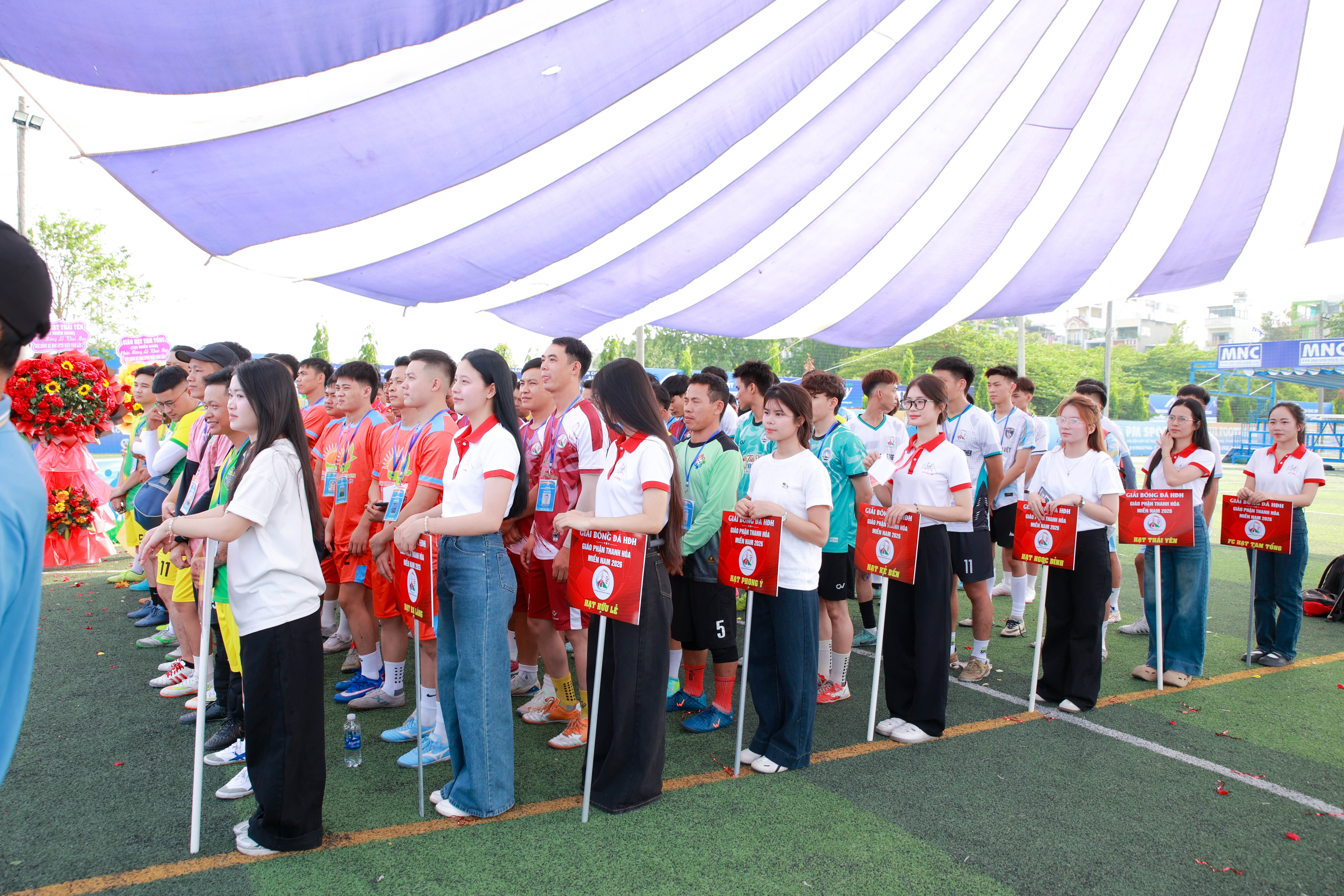Các đội bóng cầm cờ lưu niệm xếp hàng trang trọng trước sân khấu